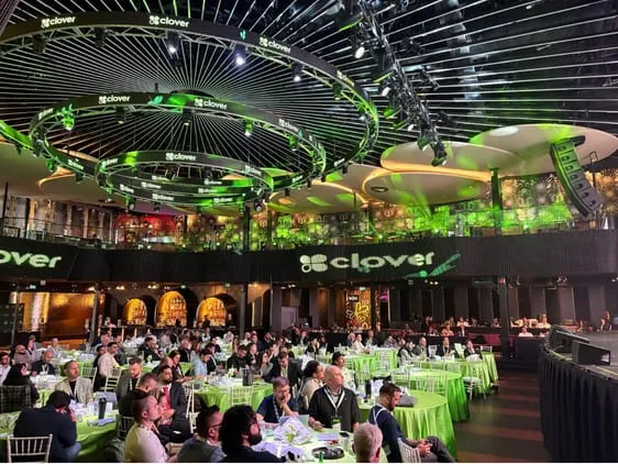 The Clover conference hall lit in green, every table full.
