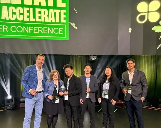 Six members of the GT Legacy team on stage with the award, under the Clover conference banner.