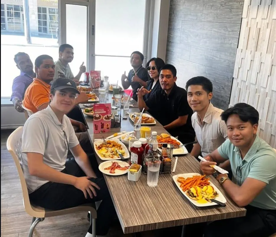 The team around a long restaurant table at breakfast, plates in front of them.