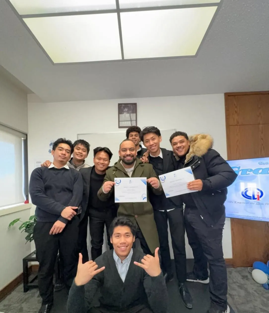 Team members in the office holding up the certificates they have just been presented.